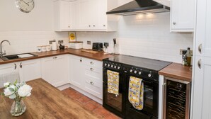 A modern kitchen with white cabinets, a black stove, and a clock on the wall. - Ivy Bank (Thornhill)