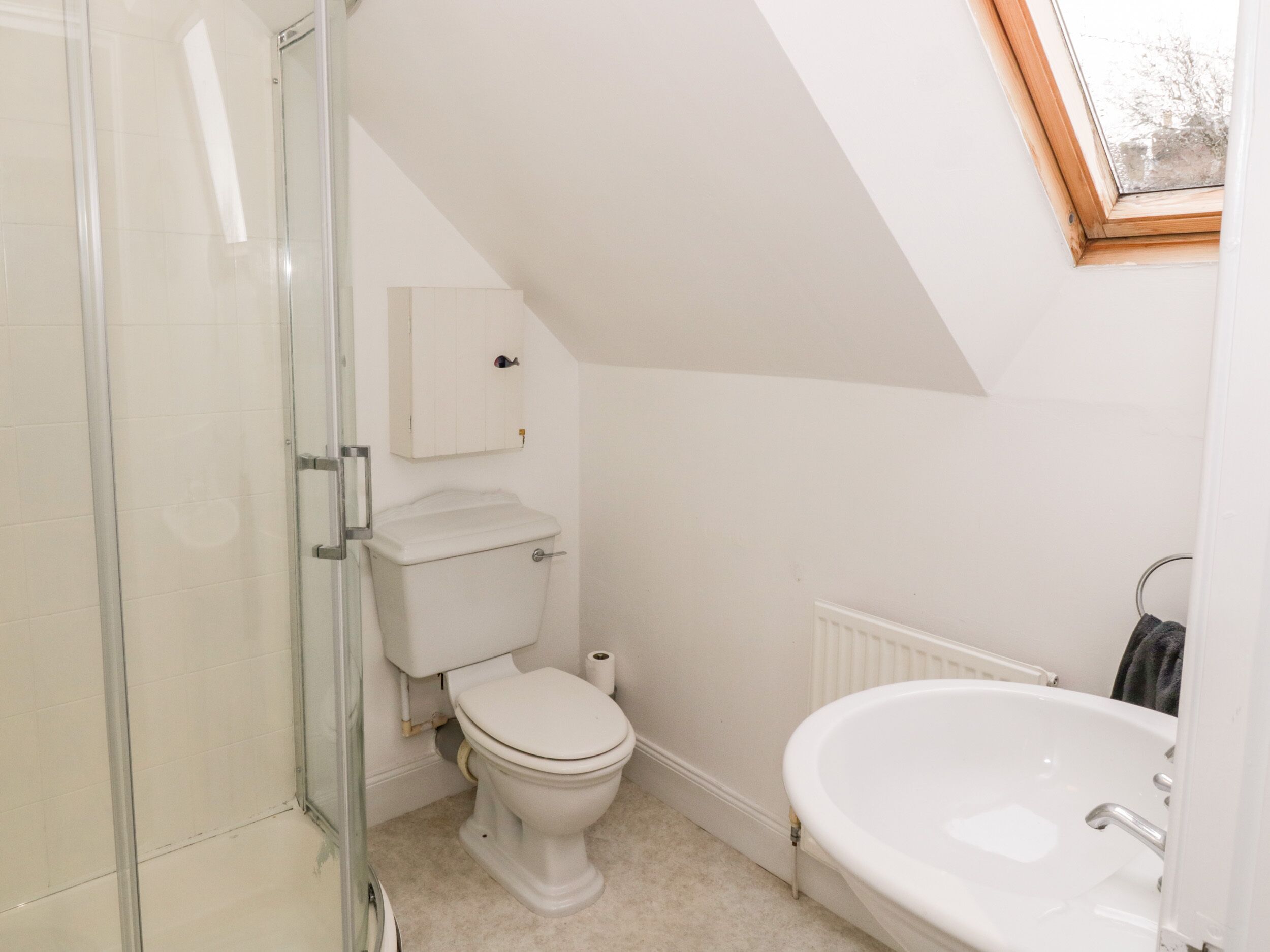 A small, white bathroom with a toilet, shower, and sink.