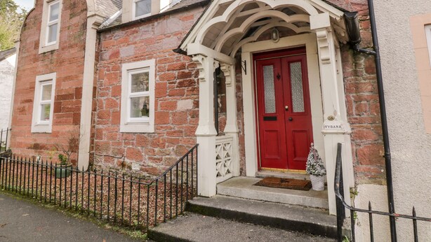 A traditional stone building with a red door and white window frames. - Ivy Bank (Thornhill)