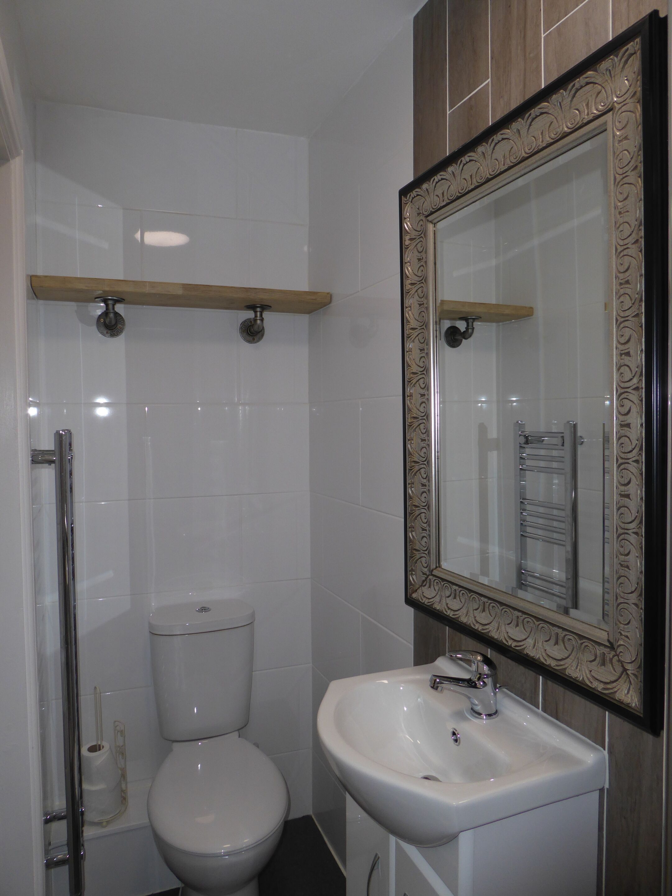 A modern bathroom with a white toilet, a sink with a decorative mirror, and a shower area.