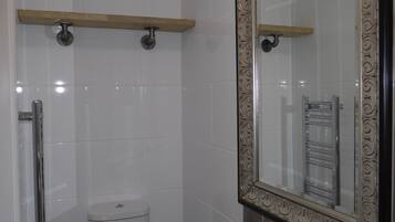 A modern bathroom with a white toilet, a sink with a decorative mirror, and a shower area.