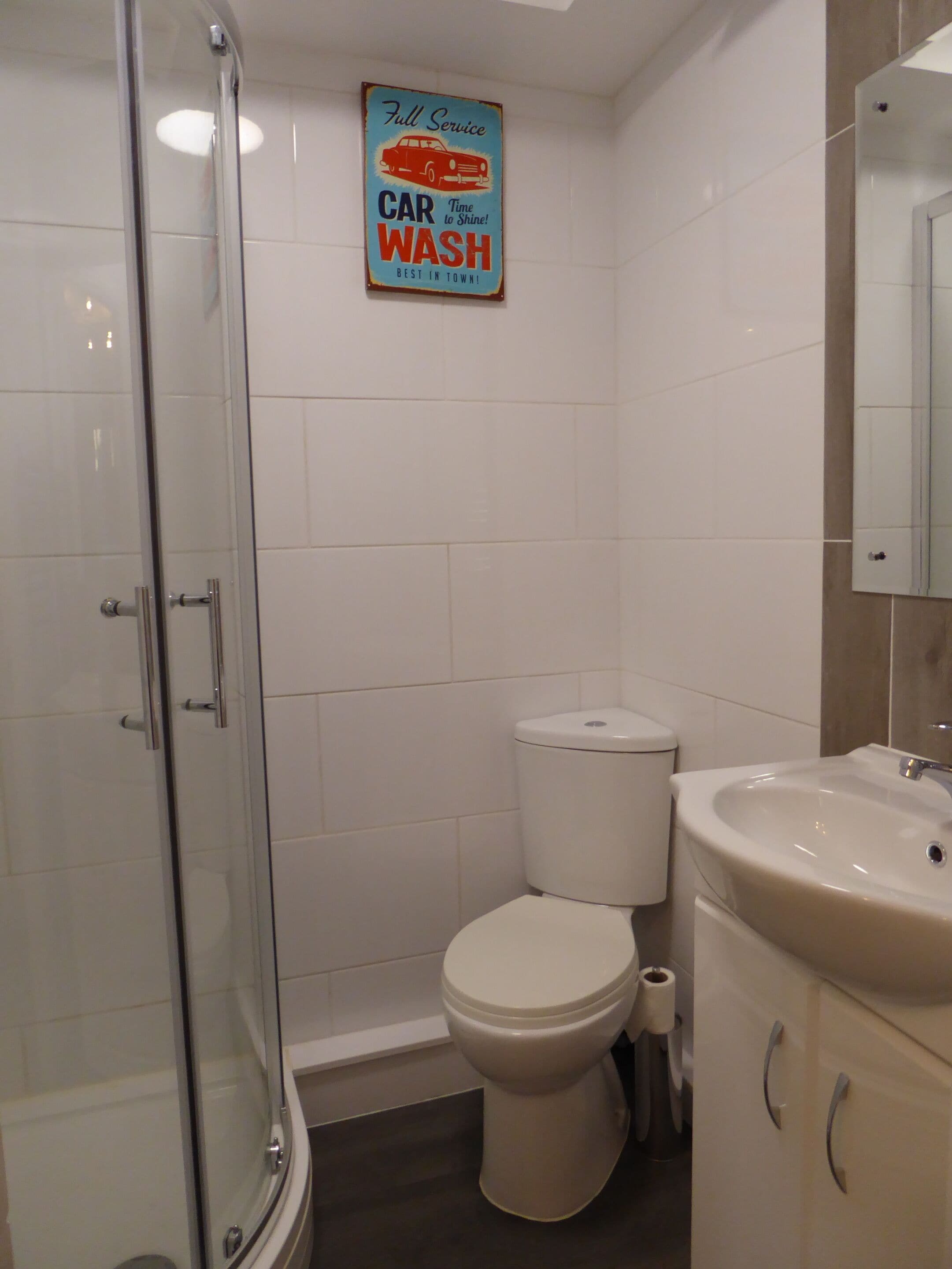 Egy fürdőszoba, amelyben üvegfalas zuhanyzó, WC és mosdókagyló található.