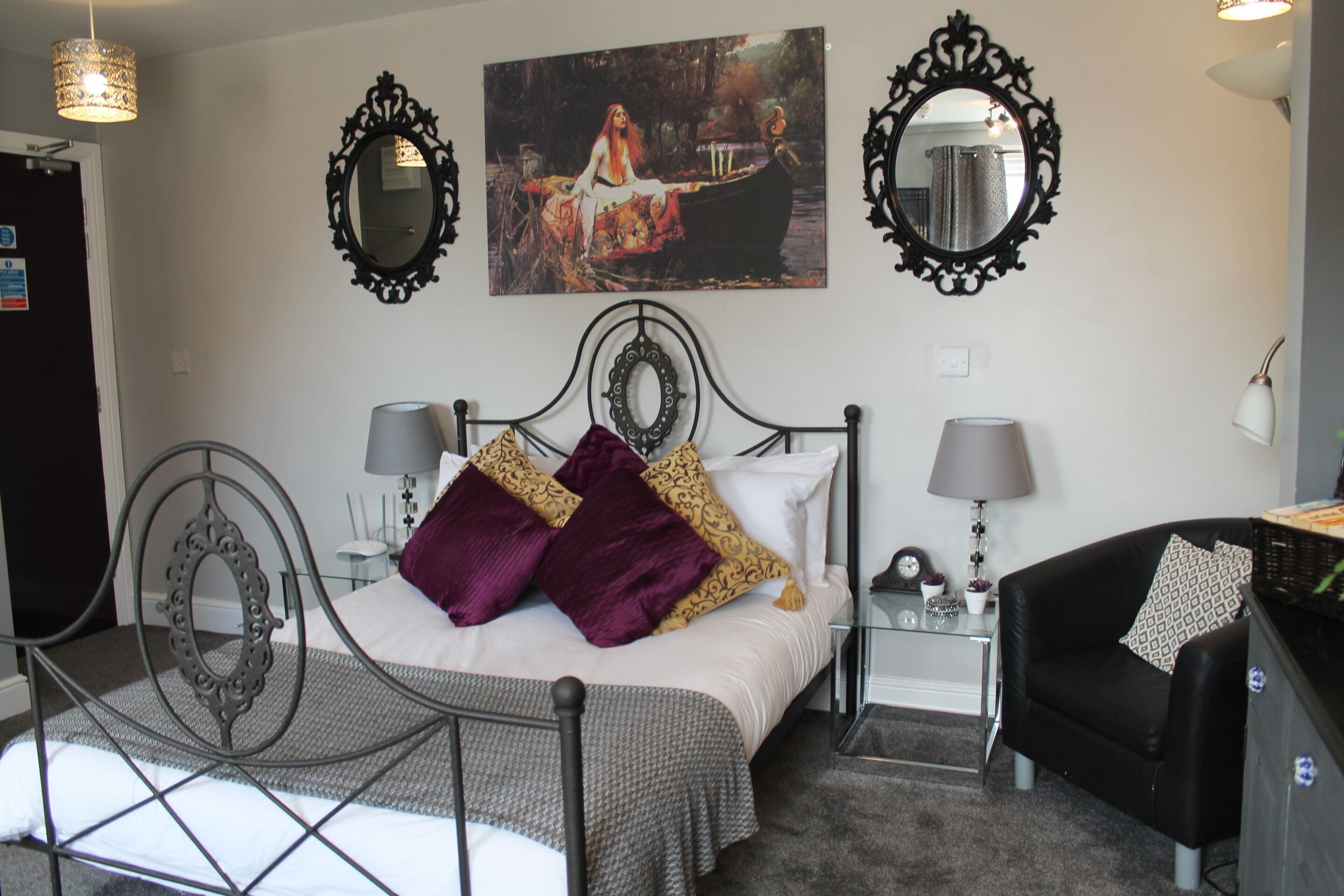 Une chambre à coucher comprenant un lit, deux tables de chevet, une chaise et des miroirs décoratifs.