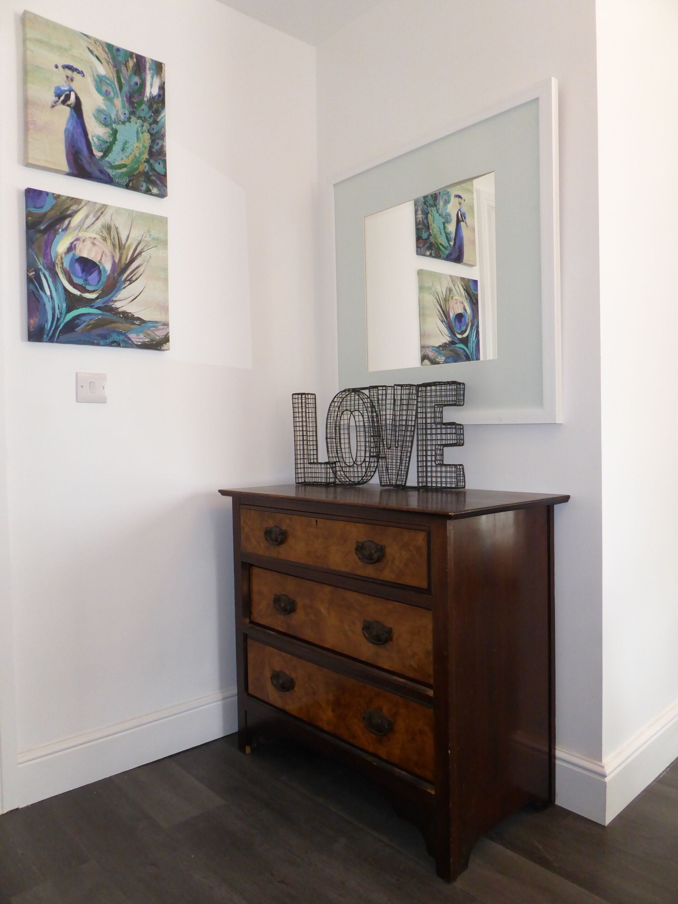A wooden dresser with three drawers and a mirror above it.