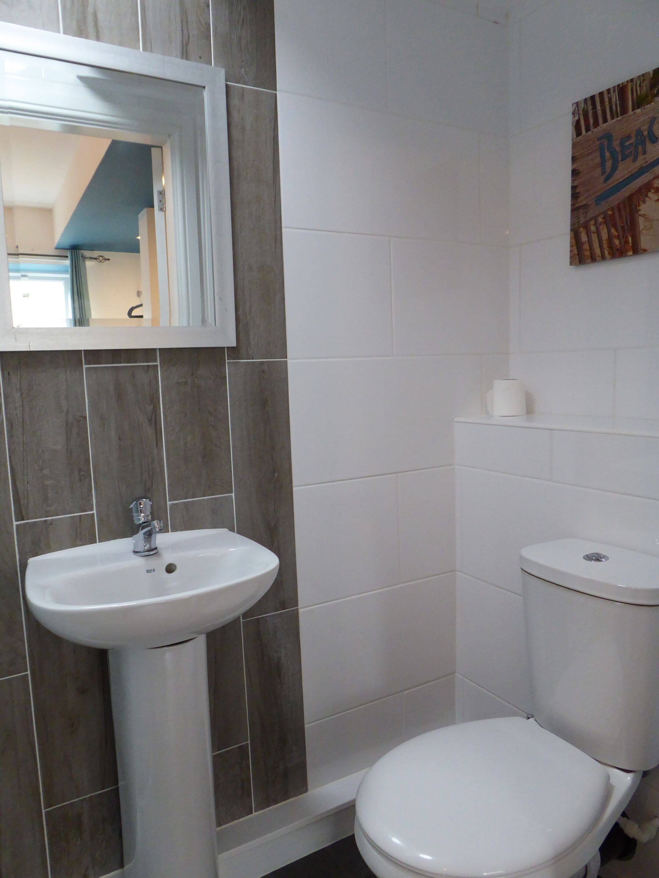 A bathroom with a white sink, a toilet, and a mirror.