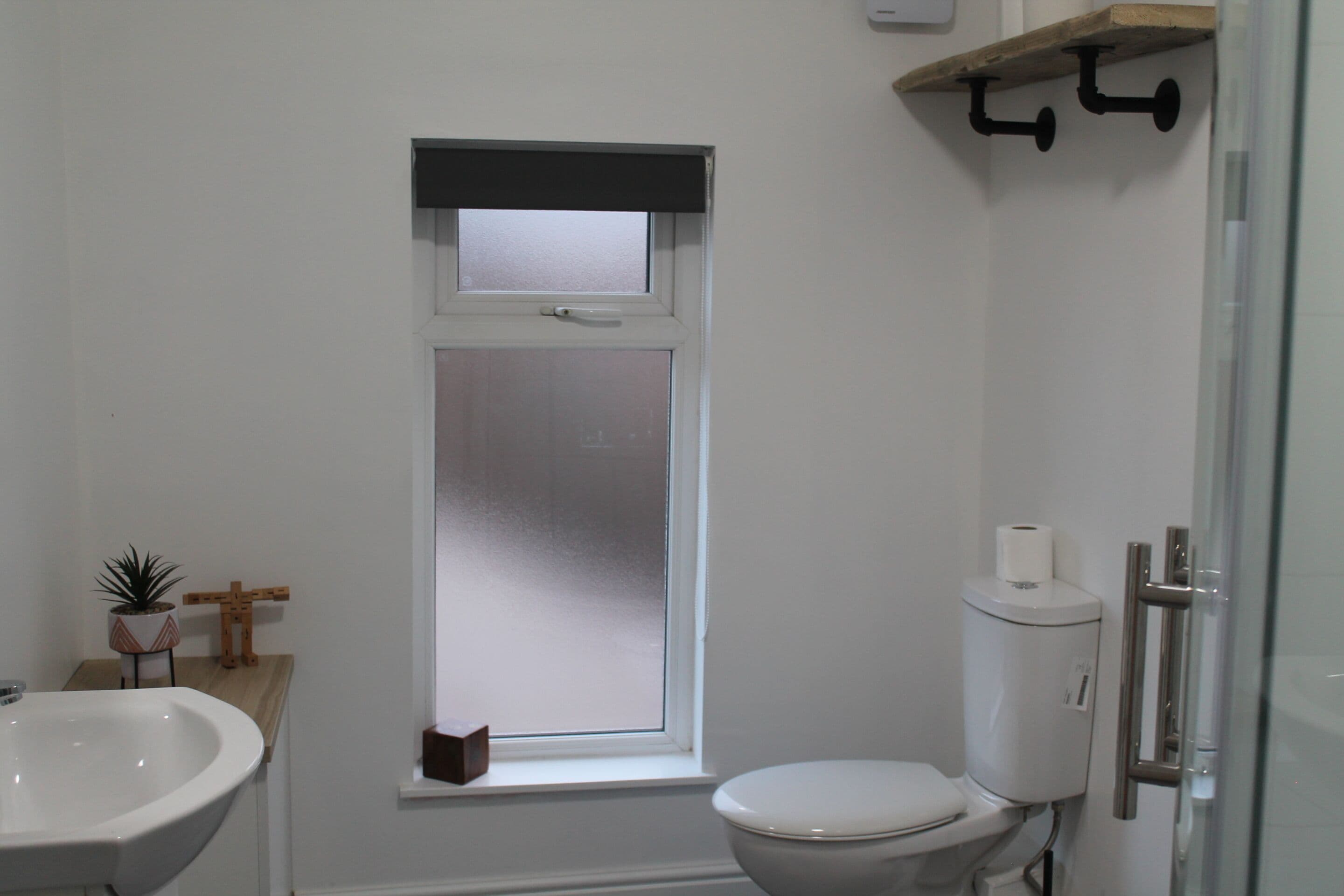 Une salle de bain comprenant des toilettes, une fenêtre, un lavabo et un espace douche.