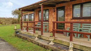Un bâtiment en bois doté d’un porche abrité, d’un espace extérieur aménagé pour s’asseoir et d’un jardin.