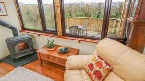Un salon chaleureux avec un canapé, une petite table agrémentée d’une plante, un bol et un poêle à bois.
