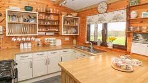 Une cuisine chaleureuse avec des meubles en bois, un grand îlot central doté d’un évier, ainsi que divers ustensiles et appareils de cuisine.