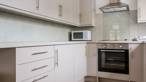 A modern kitchen with white cabinets, a microwave, and an oven.