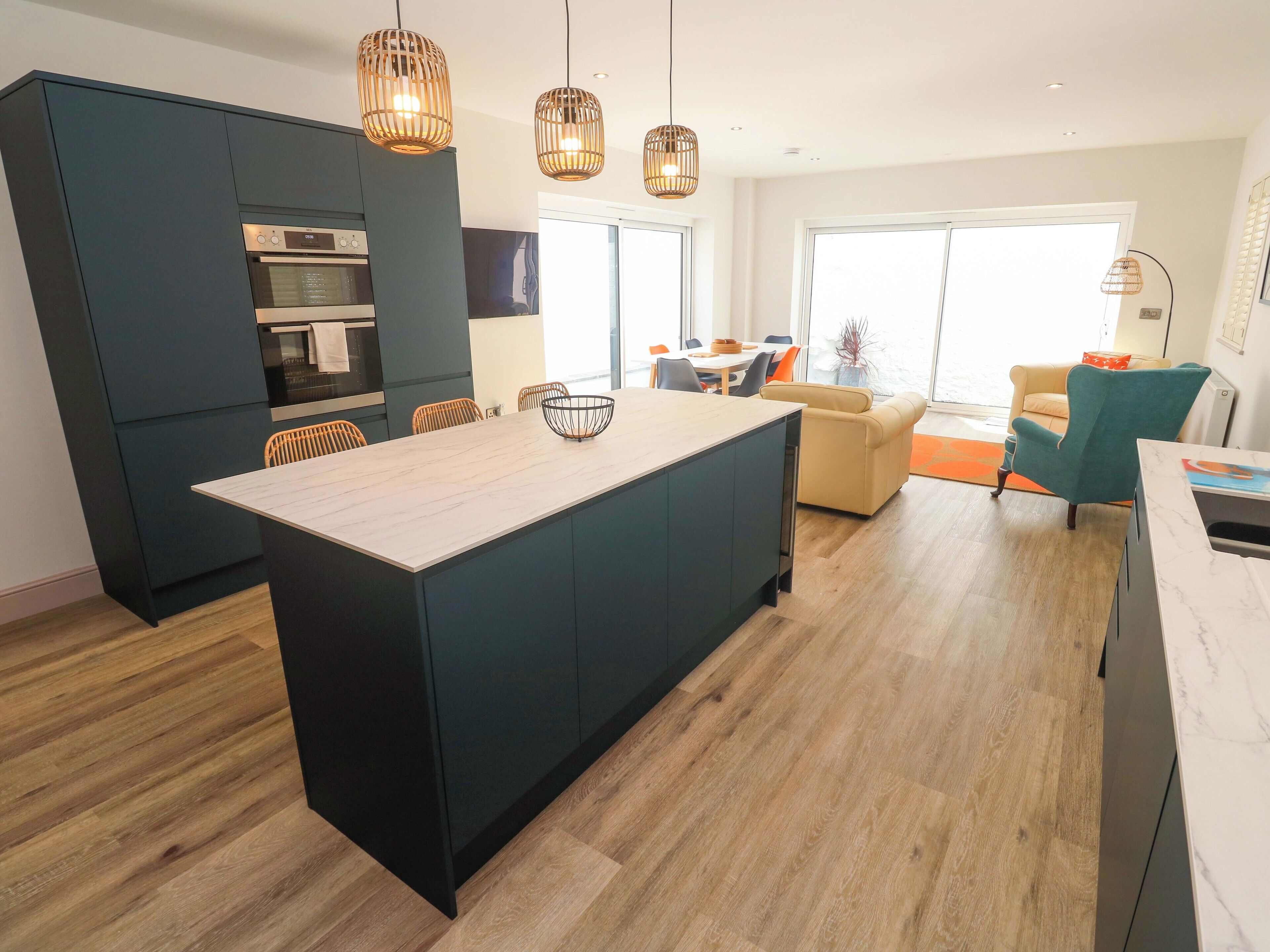 Una cocina moderna con armarios oscuros, una isla central e iluminación colgante.