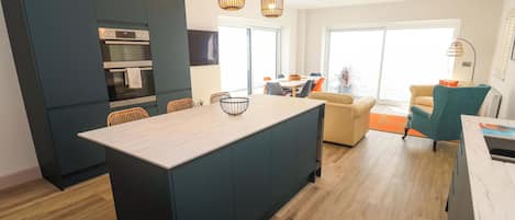 Una cocina moderna con armarios oscuros, una isla central e iluminación colgante.