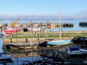 Ein Hafen mit verschiedenen Schiffen, darunter ein rotes und weißes Schiff, ein blaues Segelboot und ein weißes Boot mit blauem Verdeck.