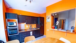 Uma cozinha compacta com eletrodomésticos modernos, uma mesa de jantar e um espelho acima.