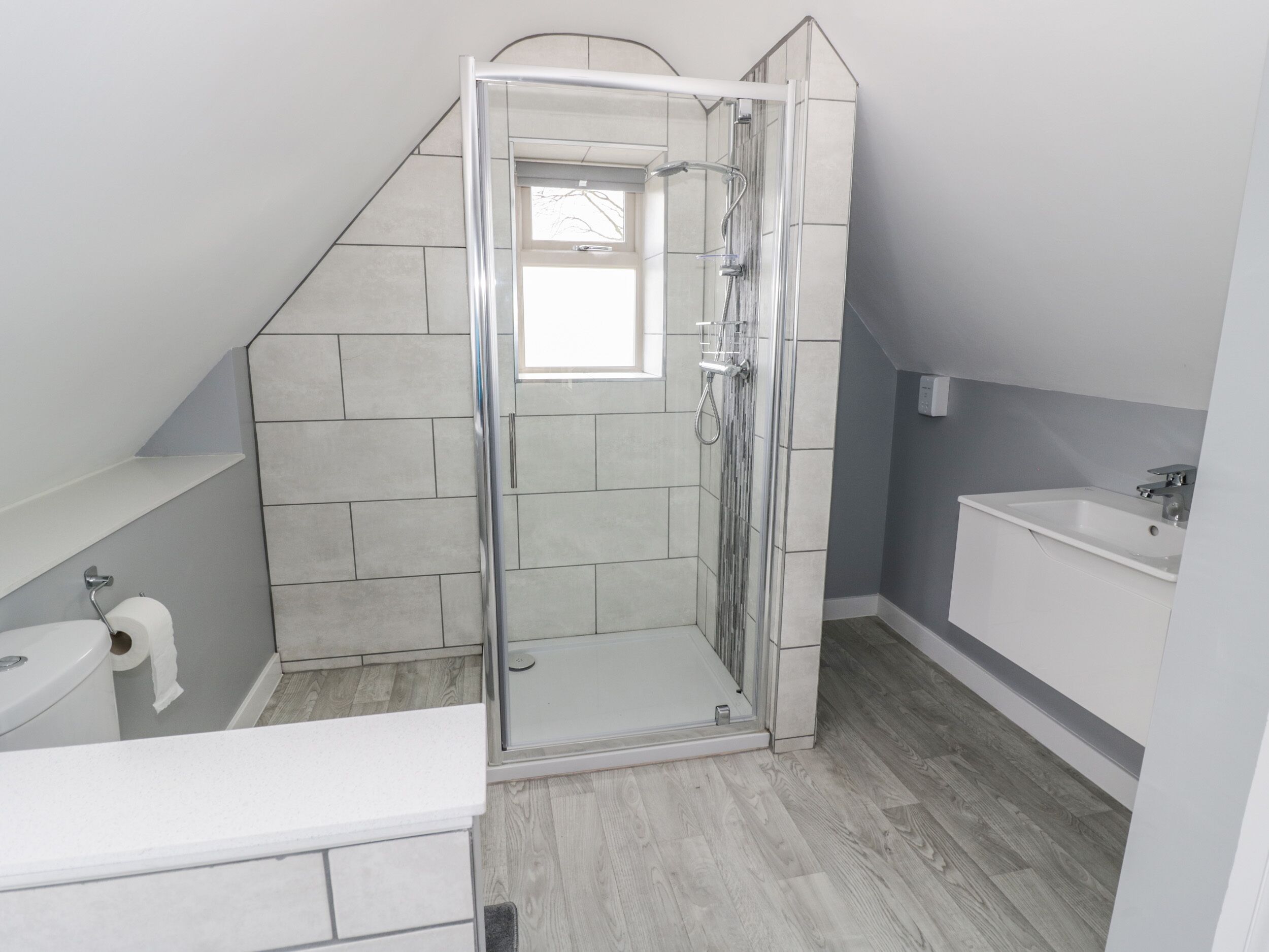 A modern bathroom with a shower enclosure, a toilet, and a sink.