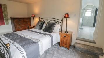 A bedroom with a bed, two bedside tables with lamps, a wooden dresser, and a large mirror.