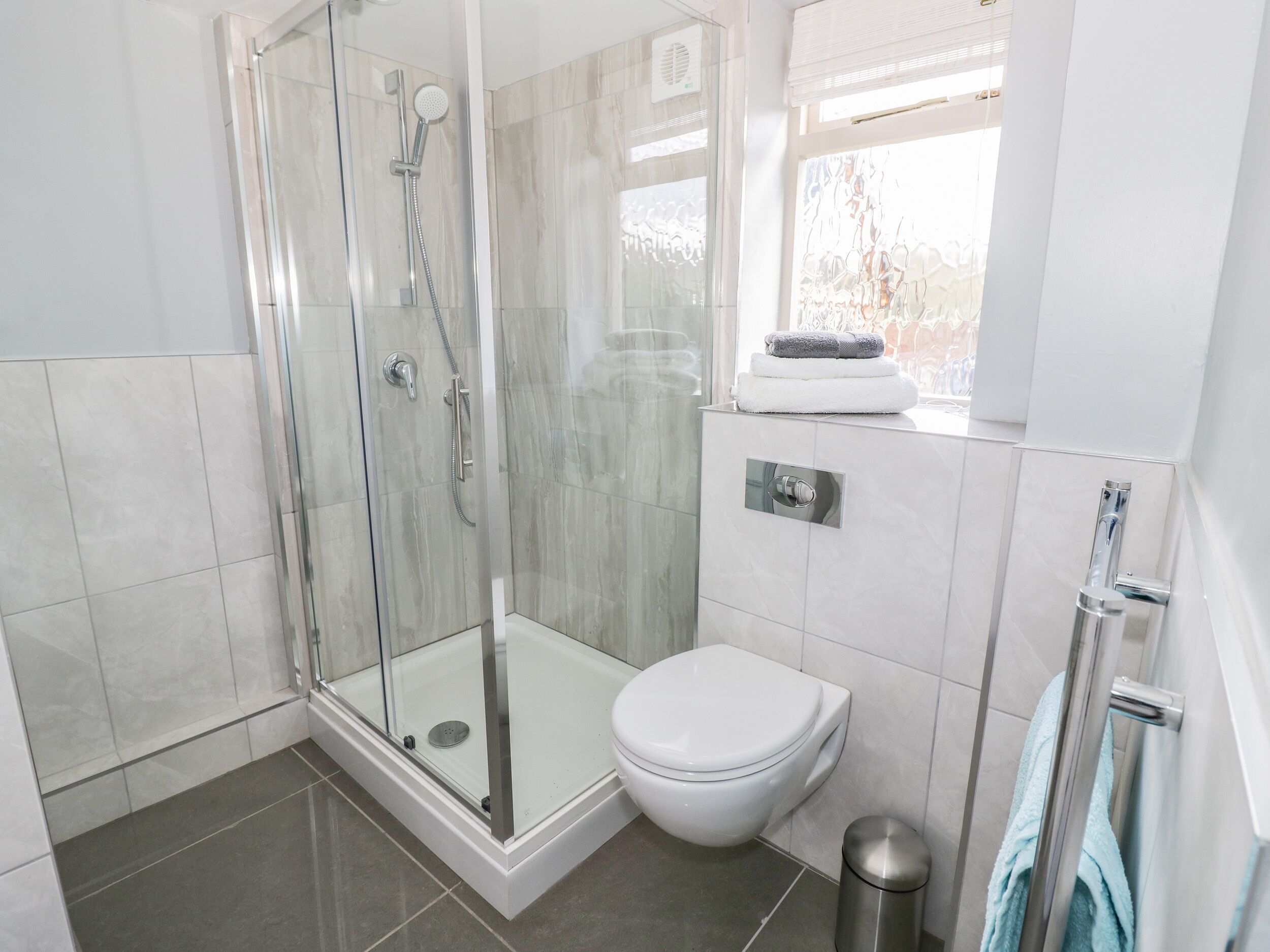A modern bathroom with a glass-enclosed shower, a toilet, and a sink.
