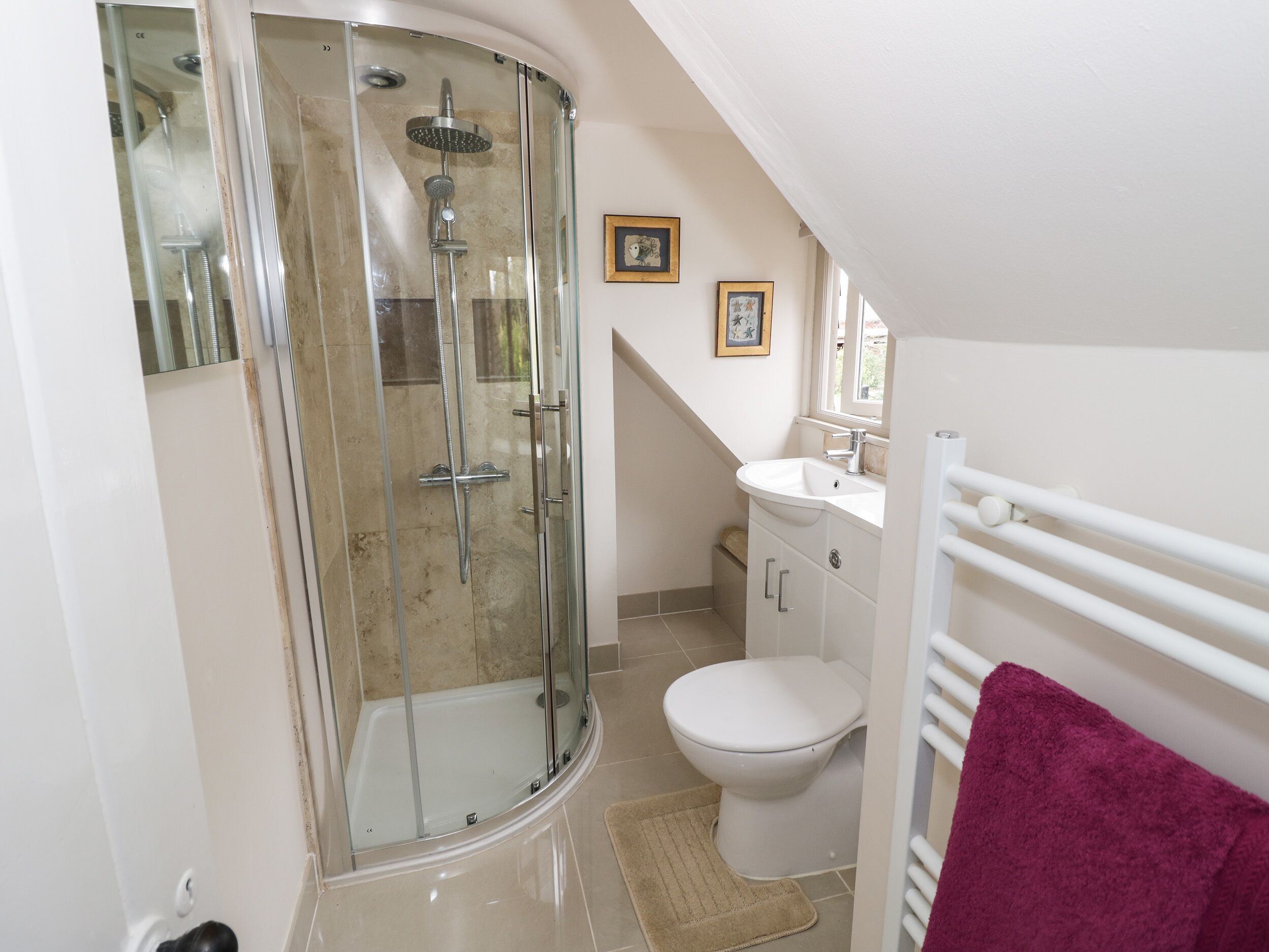A modern bathroom with a glass-enclosed shower, a white toilet, and a sink with a mirror above it.
