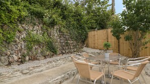 Eine Terrasse im Freien mit einer Steinsäule, einem Holzzaun und einem Tisch mit Stühlen.