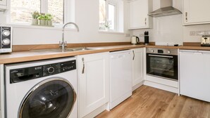 Eine moderne Küche mit weißen Schränken, einem Geschirrspüler, einem Backofen und einer Waschmaschine.