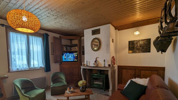 Ein gemütliches Wohnzimmer mit Holzboden, einem grünen Sessel, einem braunen Sofa, einem Holztisch und einem Kamin.