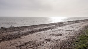 A beach with a fence and rocky terrain. - Sparrows Den Lodge (Winchelsea)