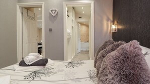 A bedroom with a bed, a fluffy pillow, a towel, and a wall-mounted light fixture. - Sparrows Den Lodge (Winchelsea)
