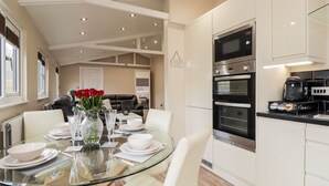 A modern kitchen with white cabinets, a built-in oven, and a coffee machine. - Sparrows Den Lodge (Winchelsea)