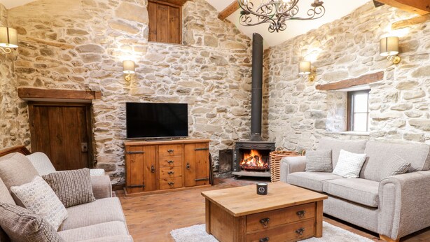 A cozy living room with stone walls, a fireplace, a television, and comfortable seating. - Groes Heol (Machynlleth)