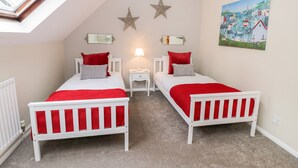 Quarto com duas camas, claraboia, decoração com estrelas, um quadro e um abajur.