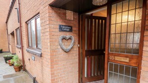 Um edifício de tijolos com uma placa que diz 'Valentines Cottage'.