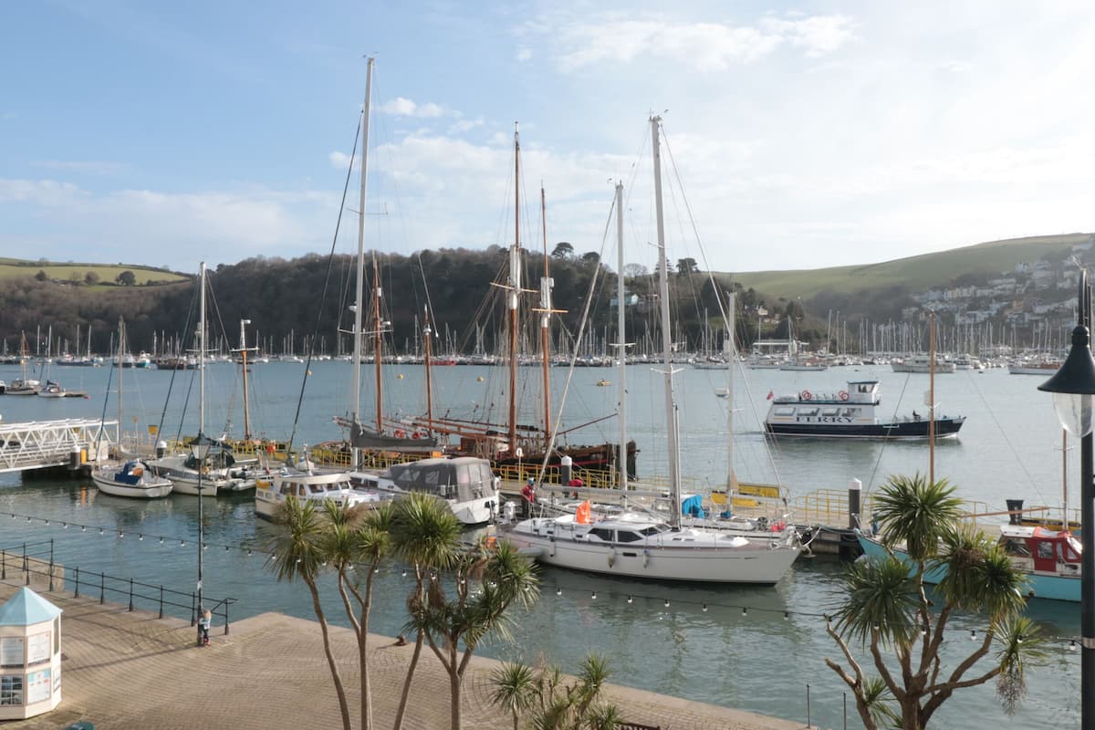 A marina with multiple boats docked, a lighthouse, and a small kiosk.