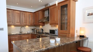A kitchen with wooden cabinets, a granite countertop, a microwave, and a gas stove. - 2 Embankment House (Dartmouth)