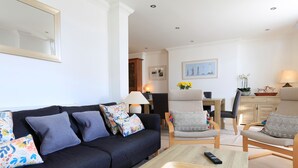 A modern living room with a dark blue sofa, a wooden coffee table, and two armchairs. - 2 Embankment House (Dartmouth)