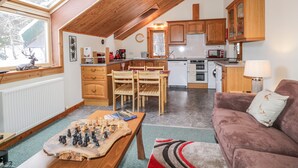 Una cocina acogedora con armarios de madera, un comedor con un tablero de ajedrez y una sala de estar con sofá.
