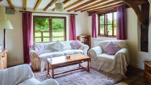 A cozy room with a wooden ceiling, two white sofas, a wooden coffee table, and a window with curtains. - The Granary (Norwich)