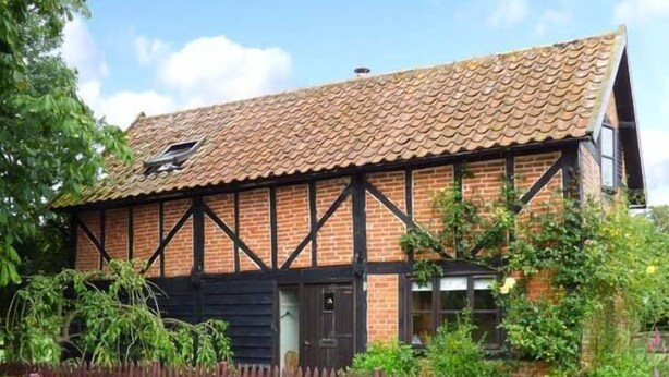 A traditional Tudor-style house with a tiled roof, brick walls, and dark timber framing. - The Granary (Norwich)
