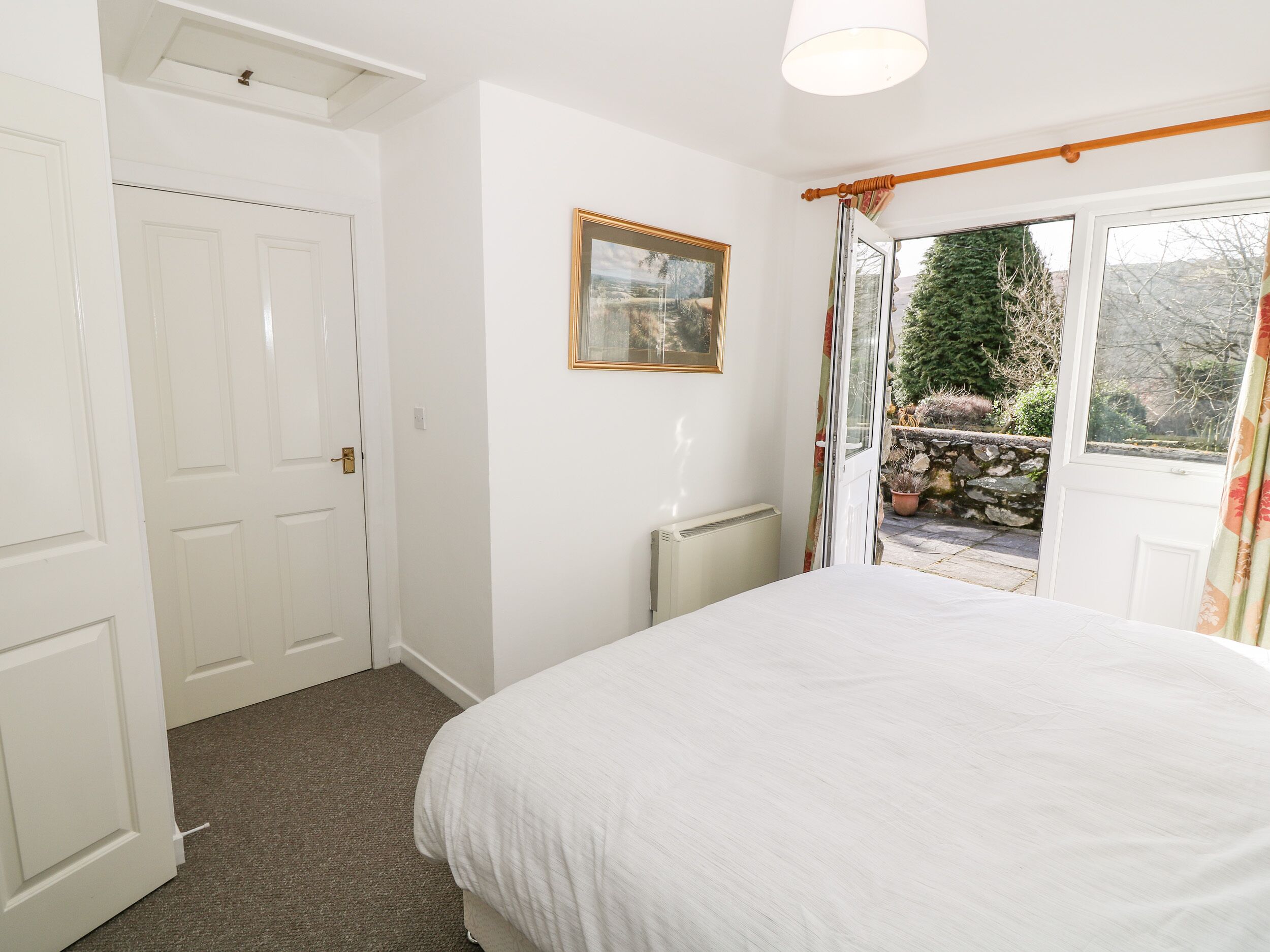 A bedroom with a bed, a radiator, a door, and a window with curtains.