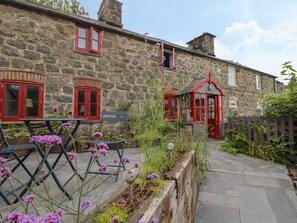 A stone building with red window frames and a small red-roofed structure. - Bwthyn Dyfi (Machynlleth)