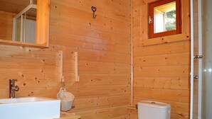 A wooden cabin bathroom with a sink, toilet, and a small window.