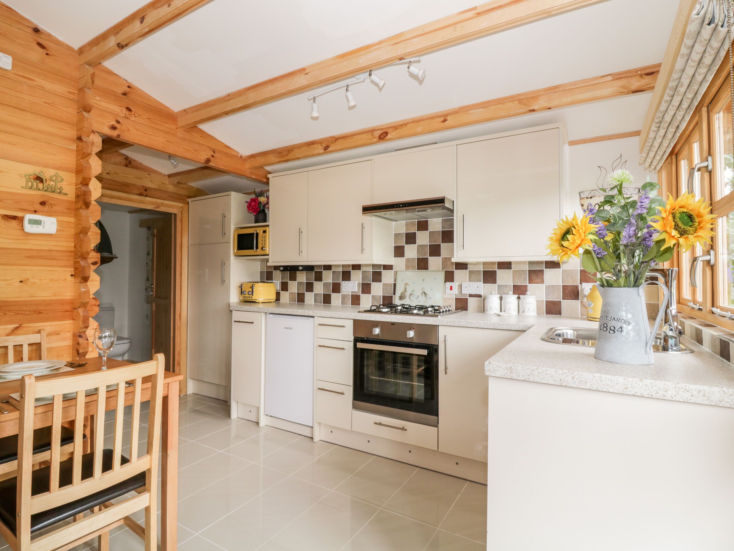 A modern kitchen with wooden beams, white cabinets, a microwave, a toaster, and a sink.