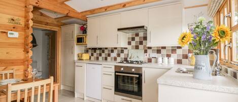 A modern kitchen with wooden beams, white cabinets, a microwave, a toaster, and a sink.