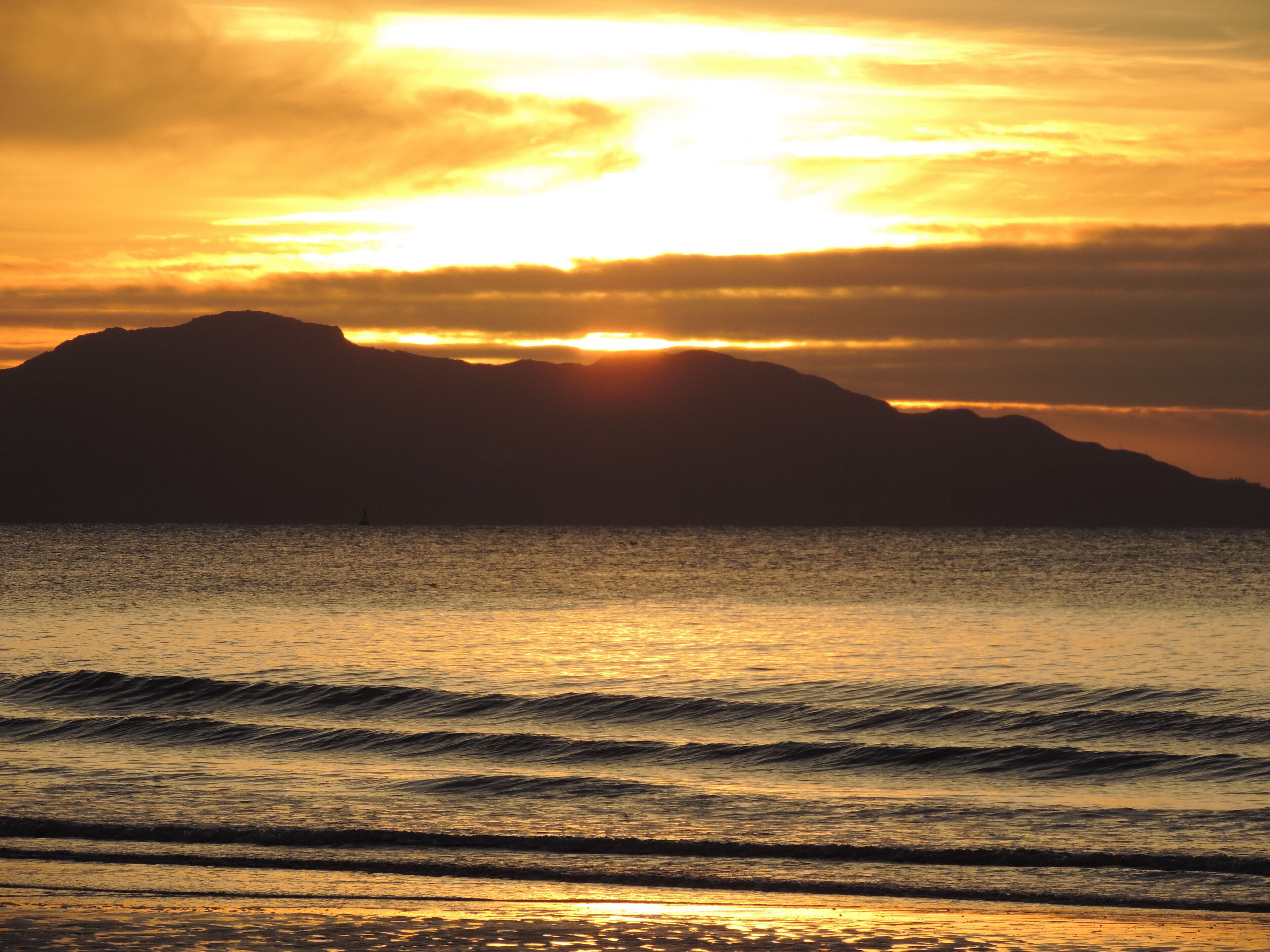 A sunset over a body of water with mountains in the background.