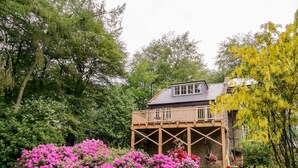 Ein Haus mit einer Holzterrasse und einem Balkon.