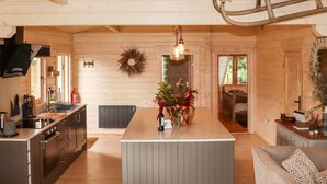 A spacious kitchen with a central island, wooden walls, and a hanging light fixture.