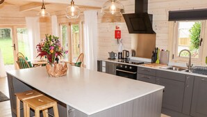 A modern kitchen with a large island, grey cabinets, stainless steel appliances, and a view of the outdoors.