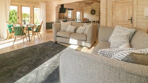 A cozy living room with a sofa, a dining table with chairs, and a kitchen area visible through an open doorway.