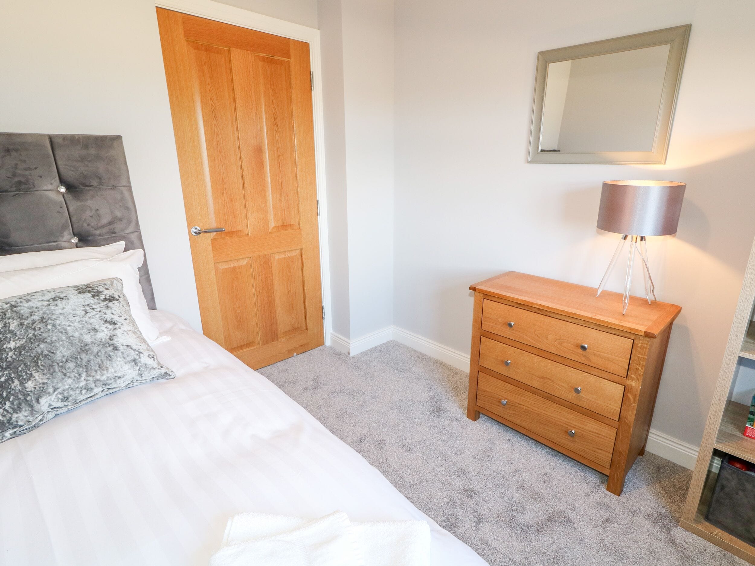 Un dormitorio con una cama, un aparador de madera, un espejo y una lámpara.