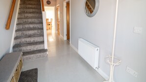 Een hal met een betegelde trap, een witte radiator en een spiegel aan de muur.