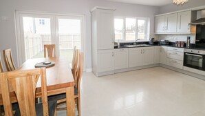 Een moderne keuken met witte kasten, een eettafel met stoelen en een groot raam.